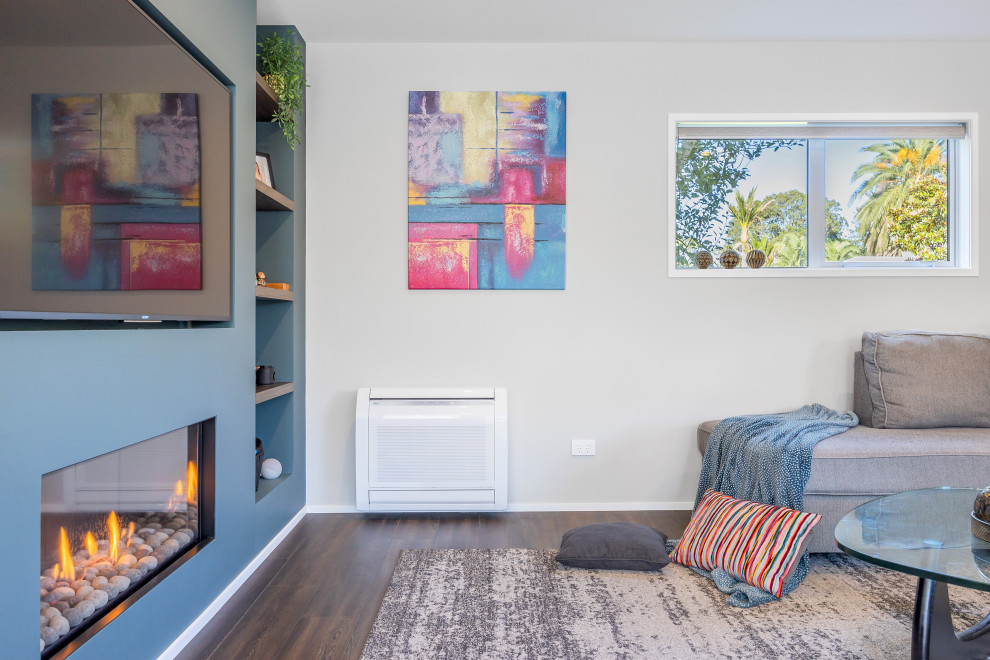 オークランドにある低価格の小さなコンテンポラリースタイルのおしゃれなLDK (緑の壁、クッションフロア、横長型暖炉、埋込式メディアウォール、茶色い床) の写真