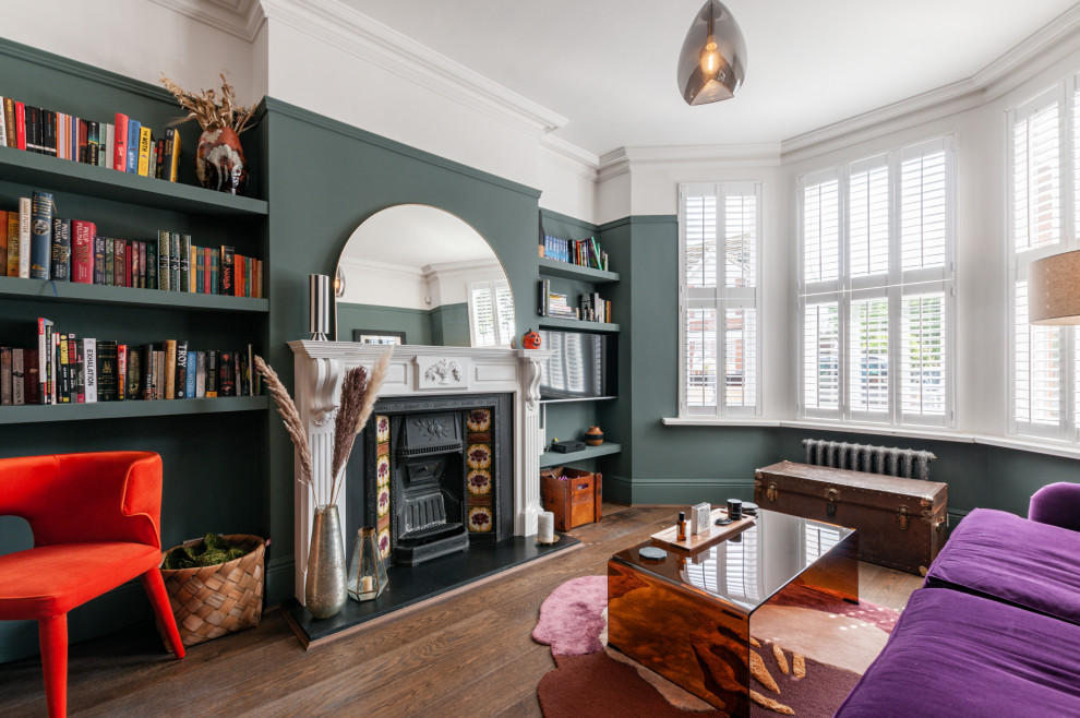 Cette photo montre un grand salon éclectique ouvert avec un mur vert, un sol en bois brun, une cheminée standard, un manteau de cheminée en pierre, un téléviseur encastré et un sol marron.