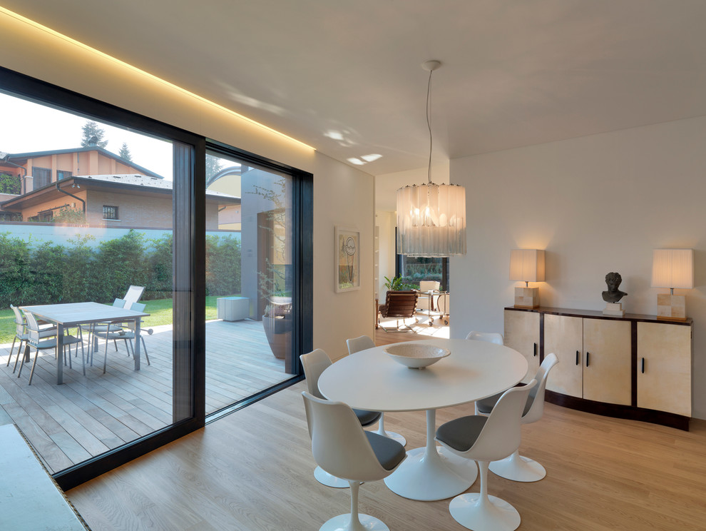 Photo of a mid-sized contemporary dining room in Bologna with white walls and light hardwood floors.