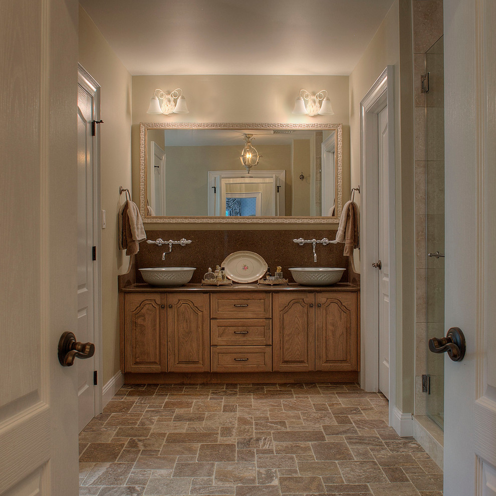 This is an example of a large country master bathroom in Philadelphia with furniture-like cabinets, light wood cabinets, an alcove shower, beige tile, porcelain tile, beige walls, travertine floors, a vessel sink and soapstone benchtops.