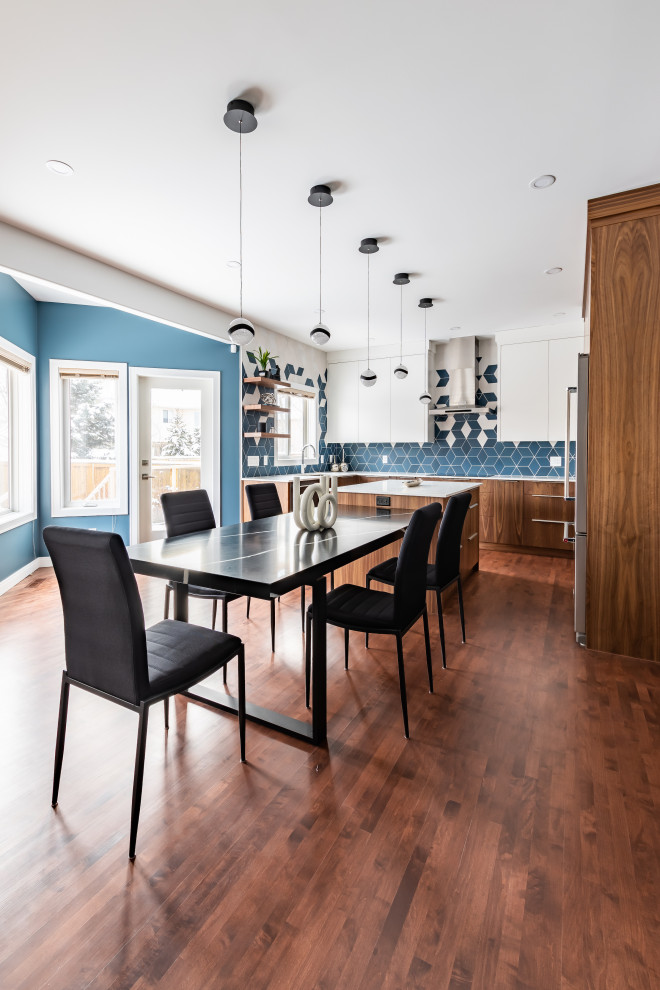 Example of a mid-sized minimalist u-shaped dark wood floor and brown floor kitchen/dining room combo design in Calgary with a double-bowl sink, flat-panel cabinets, medium tone wood cabinets, quartz countertops, multicolored backsplash, porcelain backsplash, stainless steel appliances, an island and white countertops