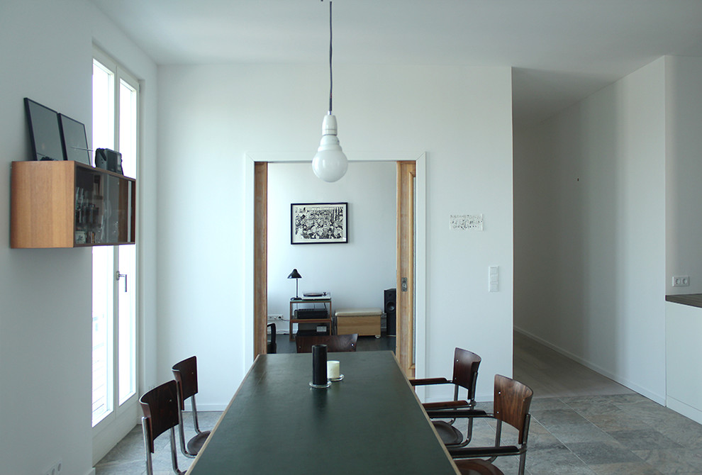 Esszimmer ohne Kamin mit weißer Wandfarbe, Betonboden und grauem Boden in Berlin