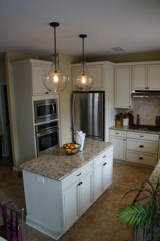 Elegant kitchen photo in Houston with an undermount sink, flat-panel cabinets, white cabinets, granite countertops, beige backsplash, stone tile backsplash, stainless steel appliances and an island