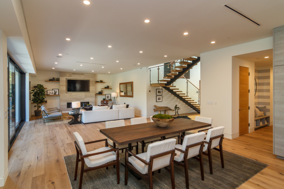 Photo of a large contemporary open plan dining in Los Angeles with white walls, medium hardwood floors, a ribbon fireplace, a tile fireplace surround and brown floor.