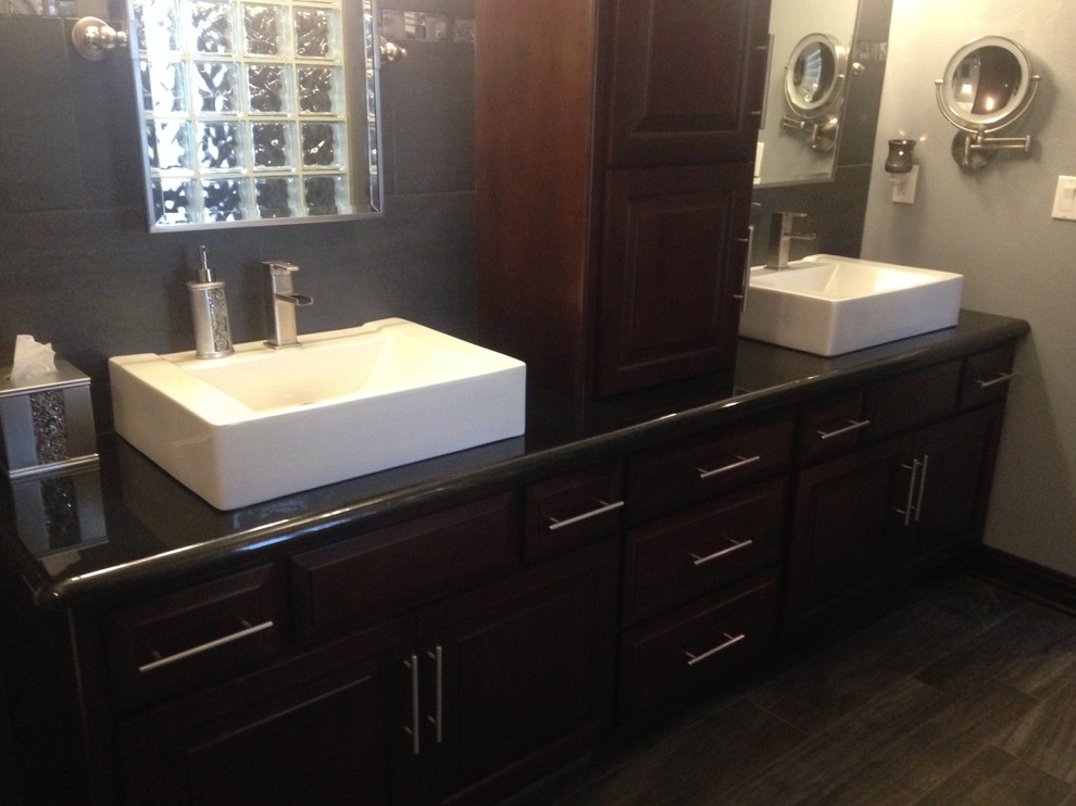 Example of a transitional bathroom design with a vessel sink, recessed-panel cabinets, dark wood cabinets, granite countertops and gray walls