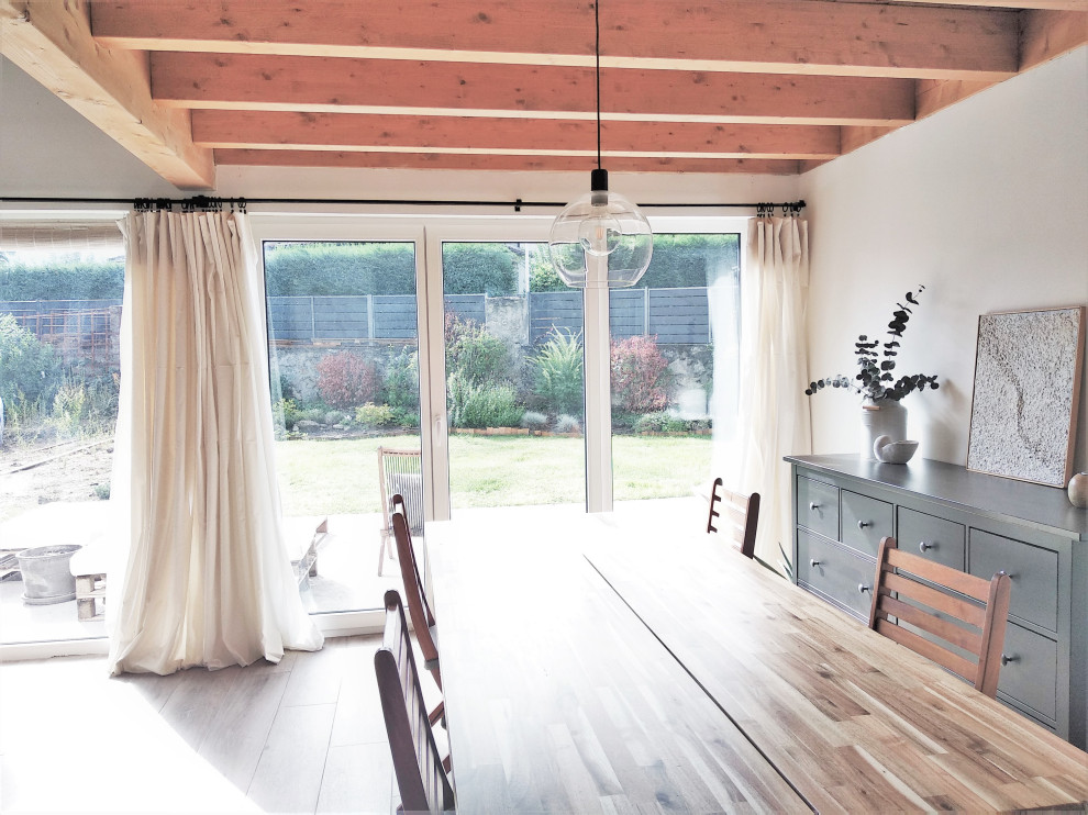 На фото: гостиная-столовая среднего размера в скандинавском стиле с белыми стенами, полом из керамогранита, коричневым полом и балками на потолке без камина с