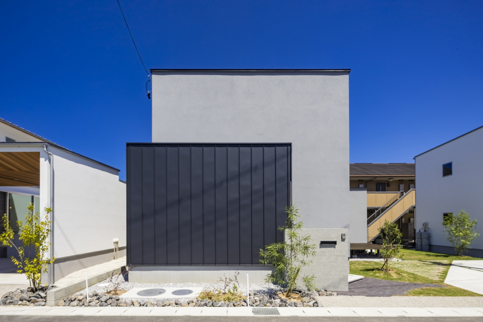 Imagen de fachada de casa gris y negra urbana de dos plantas con revestimiento de estuco y tejado de metal