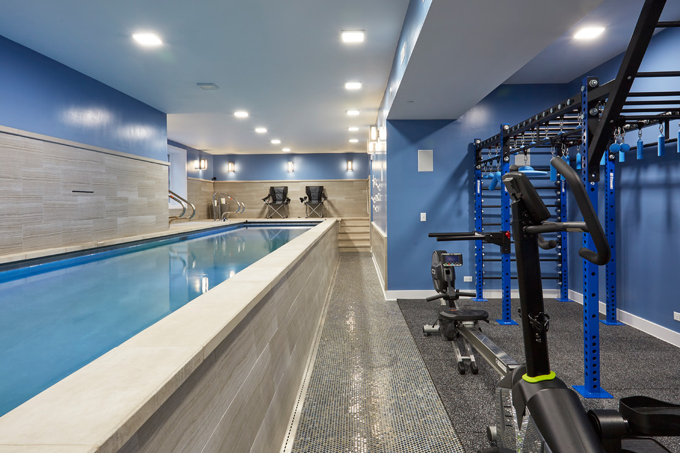 Photo of a large modern indoor rectangular lap pool in Chicago with natural stone pavers and a water feature.