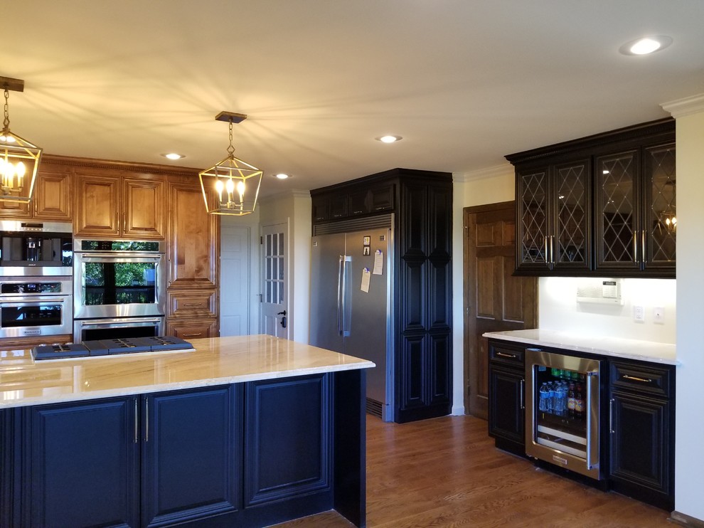 Large transitional l-shaped medium tone wood floor and brown floor open concept kitchen photo in Little Rock with an undermount sink, raised-panel cabinets, medium tone wood cabinets, quartzite countertops, white backsplash, stainless steel appliances and an island