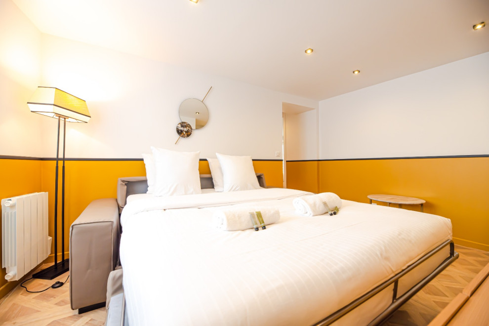 Immagine di una camera matrimoniale minimal di medie dimensioni con pareti gialle, parquet chiaro, pavimento beige e nessun camino