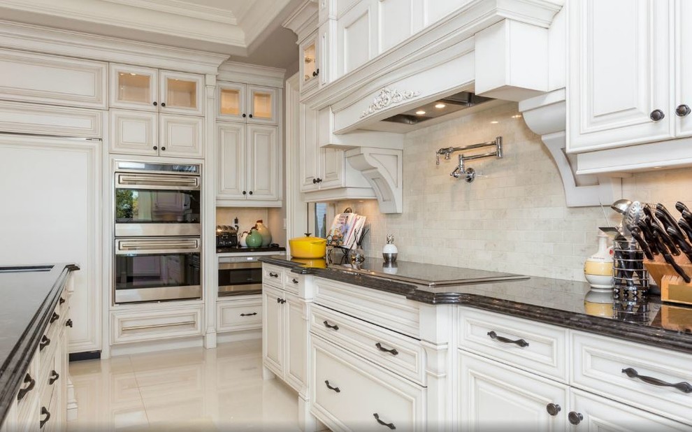 Photo of a large traditional u-shaped kitchen in Toronto with an undermount sink, raised-panel cabinets, beige cabinets, granite benchtops, beige splashback, ceramic splashback, panelled appliances, with island, beige floor and brown benchtop.