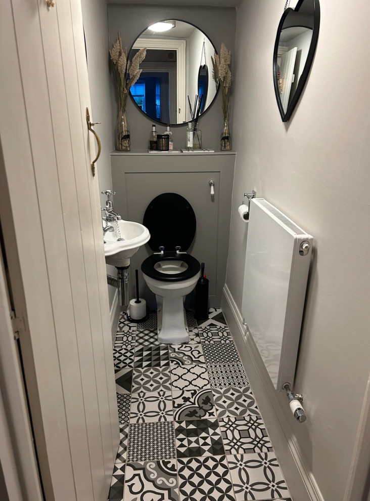 Photo of a small traditional cream and black ensuite bathroom in Berkshire with a wall mounted toilet, beige walls, cement flooring, multi-coloured floors, white worktops, a feature wall, a single sink and a built in vanity unit.