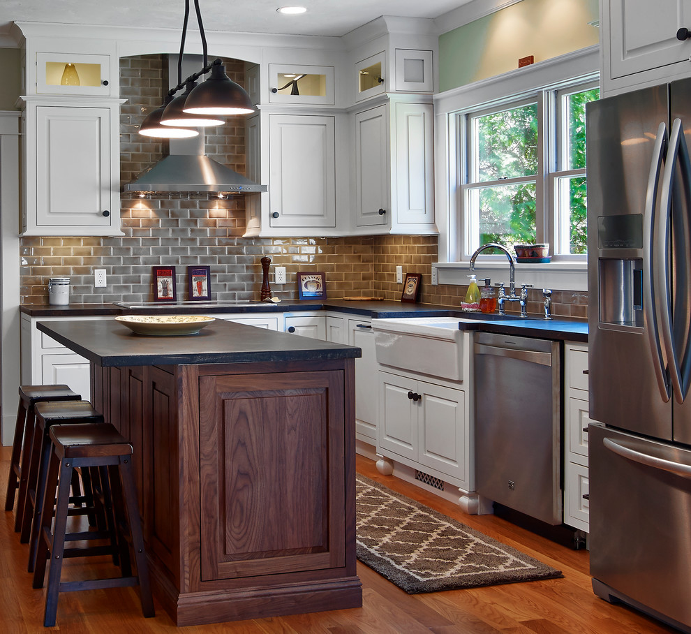 Enclosed kitchen - mid-sized transitional u-shaped medium tone wood floor and brown floor enclosed kitchen idea in Providence with a farmhouse sink, raised-panel cabinets, white cabinets, gray backsplash, subway tile backsplash, stainless steel appliances and an island