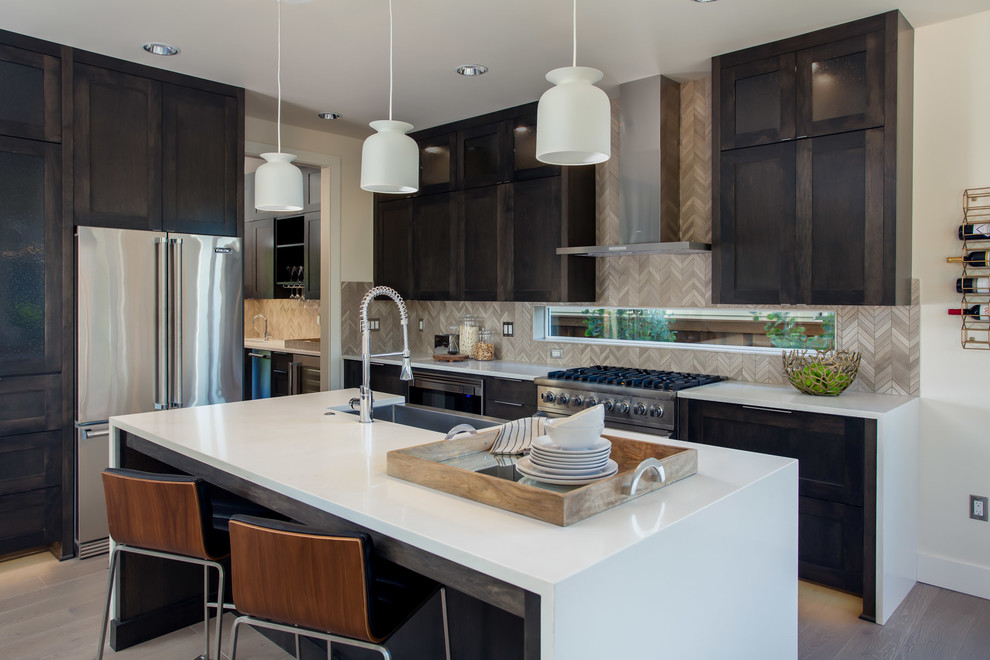 Photo of a contemporary l-shaped kitchen in Portland with a farmhouse sink, shaker cabinets, dark wood cabinets, grey splashback, stainless steel appliances, medium hardwood floors and with island.