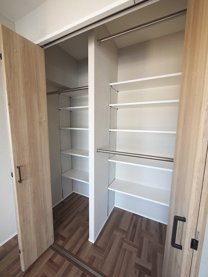 Photo of an industrial gender-neutral built-in wardrobe in Tokyo with medium wood cabinets, plywood floors and brown floor.