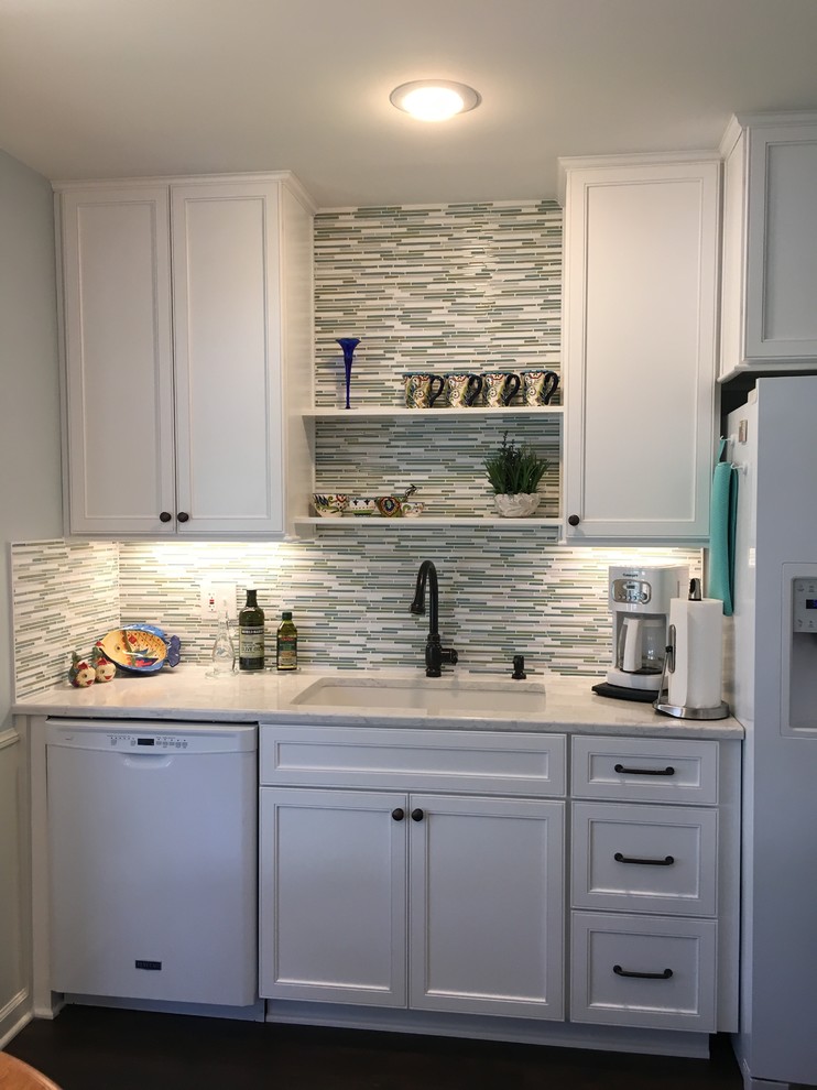 Inspiration for a mid-sized traditional l-shaped separate kitchen in Kansas City with an undermount sink, shaker cabinets, white cabinets, quartz benchtops, green splashback, mosaic tile splashback, white appliances, vinyl floors, no island and brown floor.