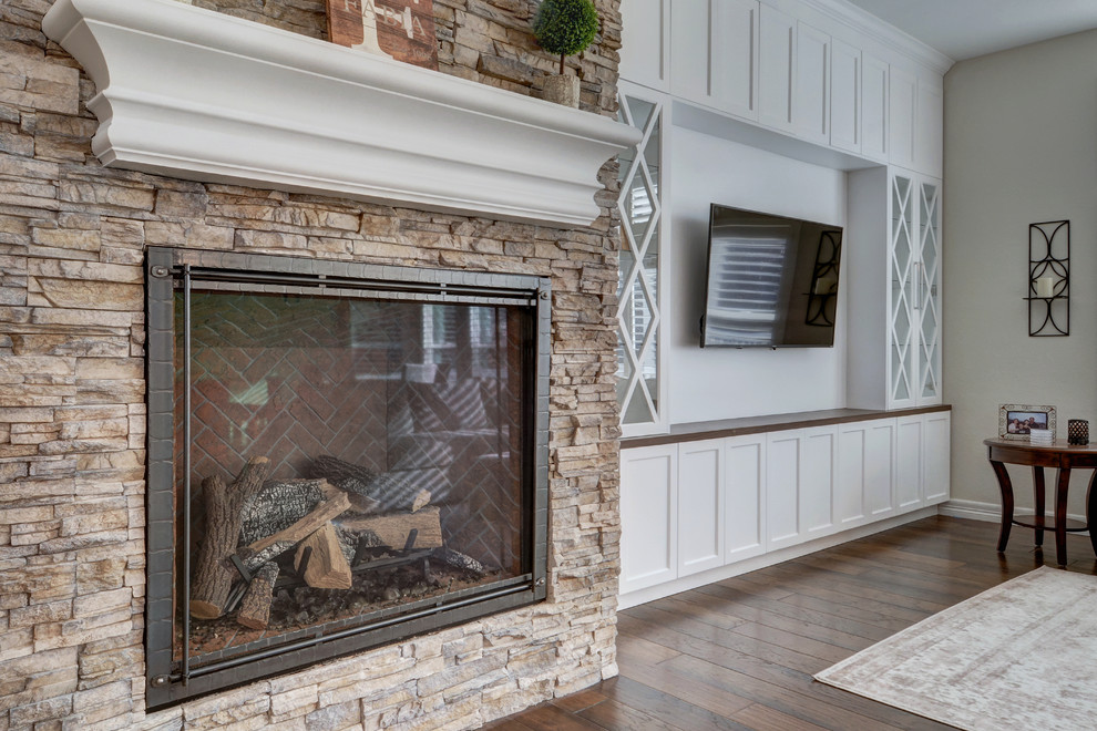 This is an example of a mid-sized transitional open concept family room in Denver with a home bar, grey walls, vinyl floors, a standard fireplace, a stone fireplace surround, a wall-mounted tv and brown floor.