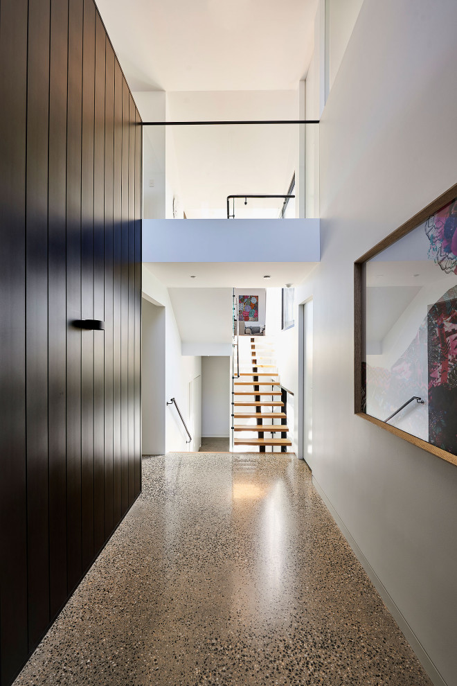 ジーロングにある高級な広いコンテンポラリースタイルのおしゃれな玄関ロビー (黒い壁、テラゾーの床、黒いドア、グレーの床、折り上げ天井、羽目板の壁) の写真