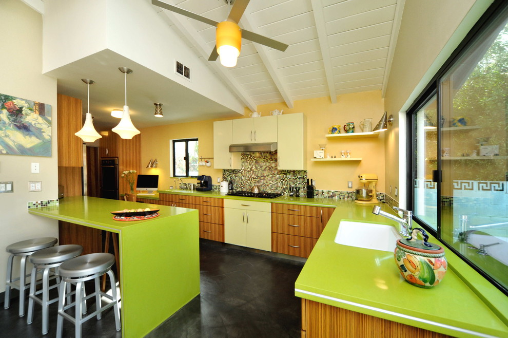 Photo of a contemporary l-shaped eat-in kitchen in Los Angeles with flat-panel cabinets, medium wood cabinets, multi-coloured splashback, mosaic tile splashback, quartz benchtops, stainless steel appliances, concrete floors, a peninsula, an undermount sink and green benchtop.