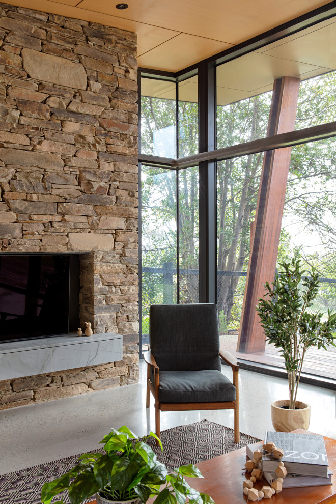 Photo of a large midcentury open concept living room in Melbourne with white walls, concrete floors, a standard fireplace, a stone fireplace surround, a concealed tv and grey floor.