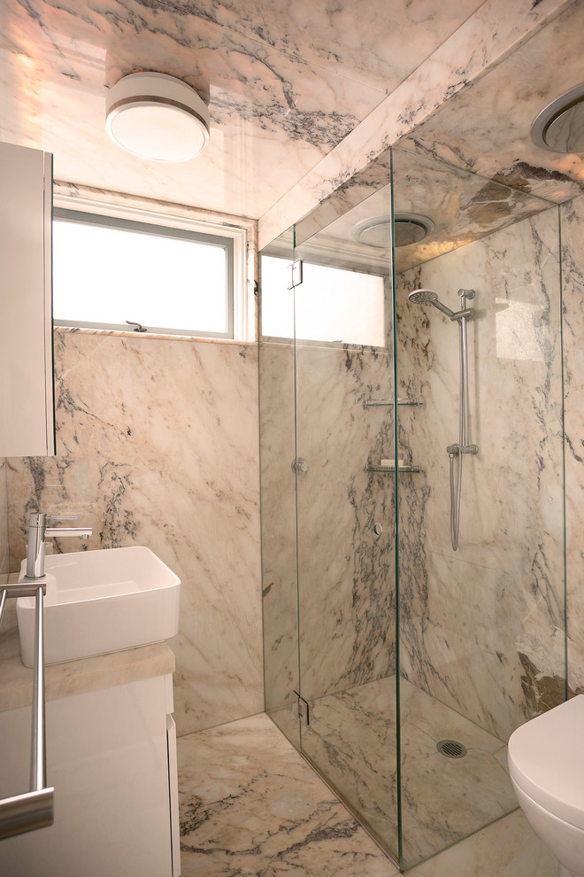 Design ideas for a small contemporary bathroom in Sydney with flat-panel cabinets, a corner shower, a one-piece toilet, white tile, stone slab, pink walls, marble floors, onyx benchtops, pink floor, a hinged shower door and pink benchtops.