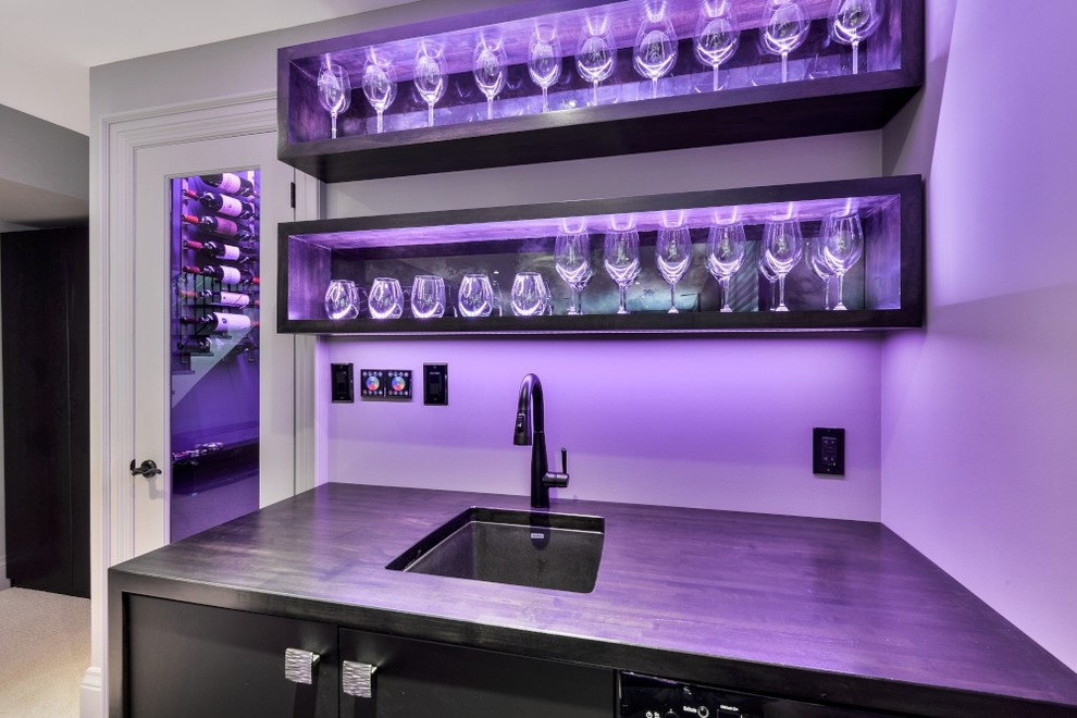 Inspiration for a large modern l-shaped wet bar in Toronto with flat-panel cabinets, black cabinets and wood benchtops.