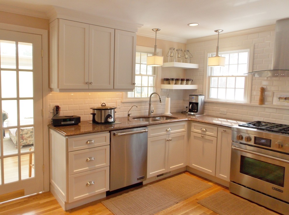 Example of a small transitional u-shaped medium tone wood floor eat-in kitchen design in Boston with an undermount sink, shaker cabinets, white cabinets, solid surface countertops, white backsplash, ceramic backsplash, stainless steel appliances and beige walls