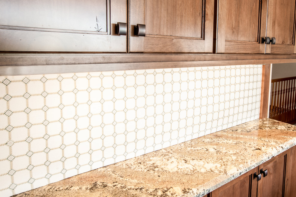 Inspiration for a mid-sized rustic u-shaped medium tone wood floor and brown floor enclosed kitchen remodel in Omaha with an undermount sink, shaker cabinets, dark wood cabinets, granite countertops, beige backsplash, travertine backsplash, stainless steel appliances, an island and multicolored countertops