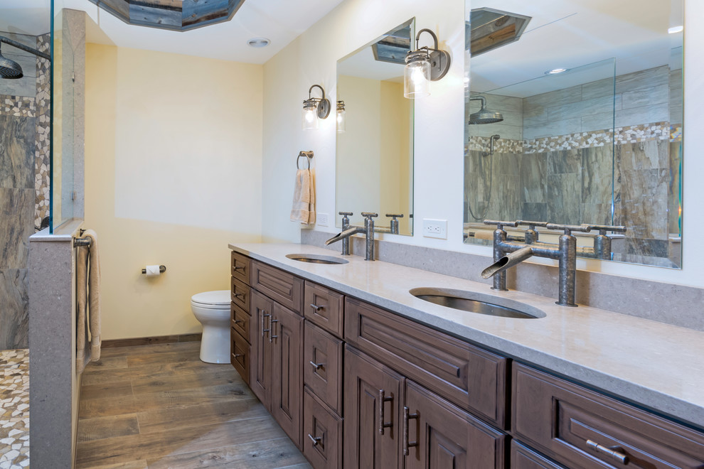 Design ideas for a large country master bathroom in Philadelphia with raised-panel cabinets, distressed cabinets, a curbless shower, a two-piece toilet, gray tile, porcelain tile, beige walls, porcelain floors, engineered quartz benchtops, brown floor, an open shower and beige benchtops.