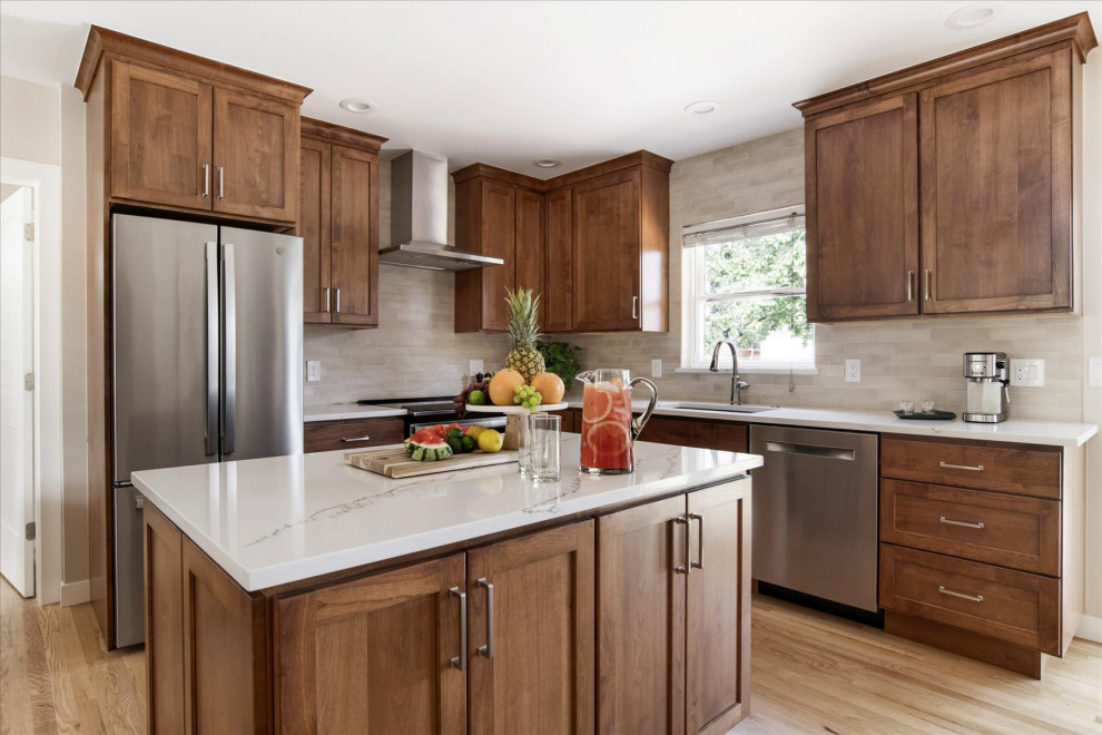 Small transitional l-shaped light wood floor and brown floor eat-in kitchen photo in Denver with an undermount sink, shaker cabinets, medium tone wood cabinets, beige backsplash, stainless steel appliances, an island and white countertops