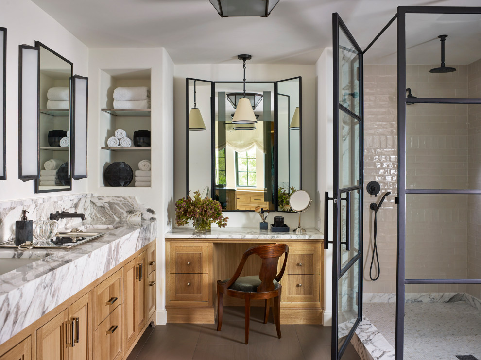 This is an example of a mid-sized transitional master bathroom in Austin with recessed-panel cabinets, subway tile, white walls, cement tiles, marble benchtops, grey floor, a hinged shower door, white benchtops, a double vanity, a built-in vanity, light wood cabinets, a corner shower, beige tile and an undermount sink.