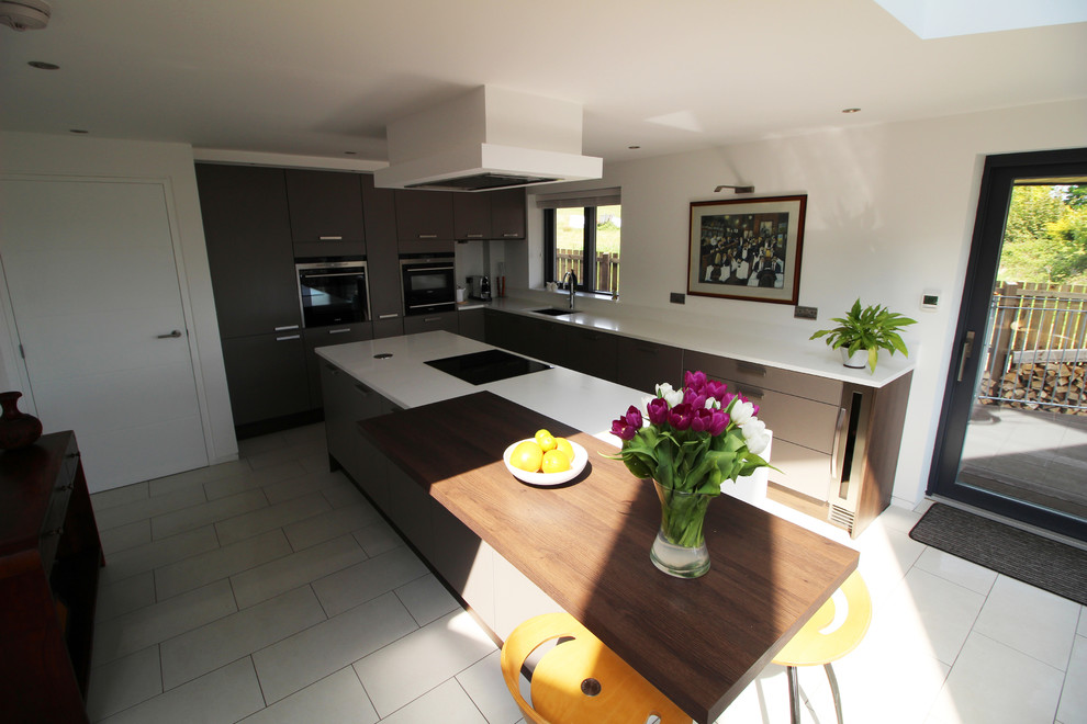 This is an example of a mid-sized contemporary l-shaped open plan kitchen in Glasgow with a drop-in sink, flat-panel cabinets, grey cabinets, quartzite benchtops, white splashback, panelled appliances, ceramic floors, with island and white floor.
