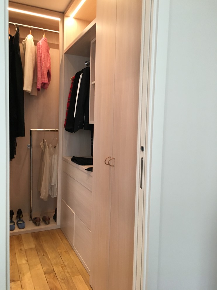 This is an example of a small transitional gender-neutral dressing room in Paris with light wood cabinets, light hardwood floors and brown floor.
