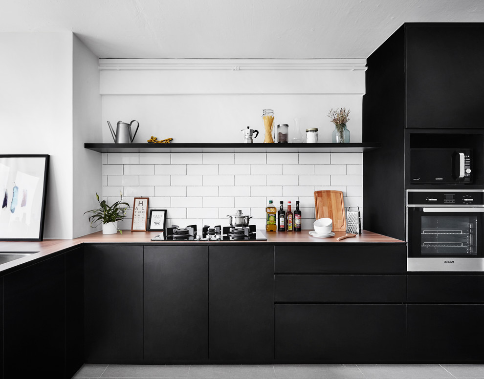 Inspiration for a contemporary l-shaped kitchen in Singapore with flat-panel cabinets, black cabinets, white splashback, subway tile splashback, stainless steel appliances, grey floor and beige benchtop.