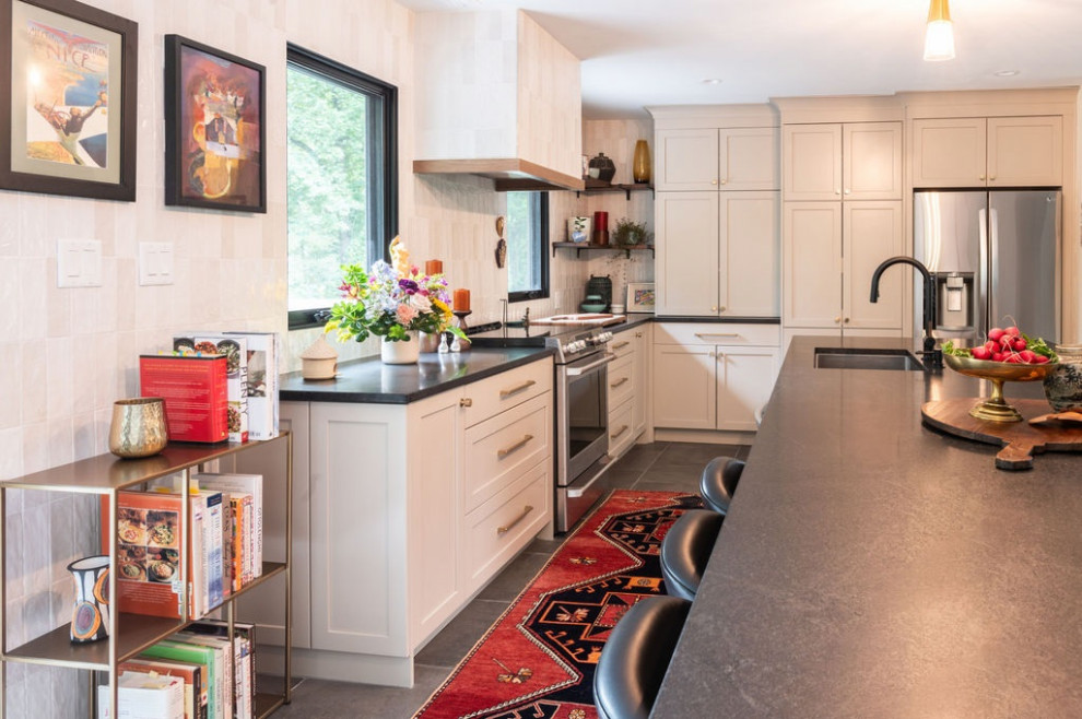 Inspiration for a transitional black floor kitchen remodel with an island, an undermount sink, shaker cabinets, beige cabinets, quartz countertops, beige backsplash, porcelain backsplash, stainless steel appliances and black countertops