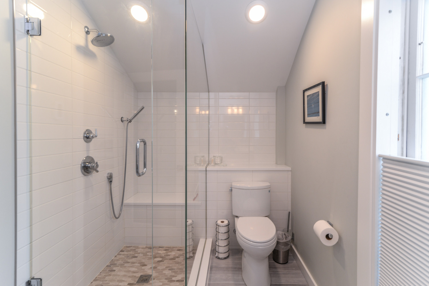The loft bathroom packs a lot in to a smaller space. The wall tile runs the length of the bathroom to create a larger appearance, plumbing is hidden in a shelf/ledge created with a waterfall edge of q