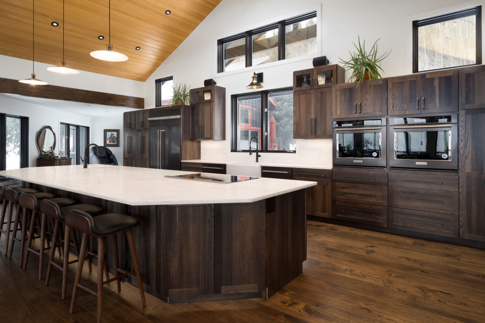 Inspiration for a huge transitional single-wall dark wood floor, brown floor and shiplap ceiling open concept kitchen remodel in Denver with a farmhouse sink, shaker cabinets, dark wood cabinets, marble countertops, paneled appliances, an island and white countertops