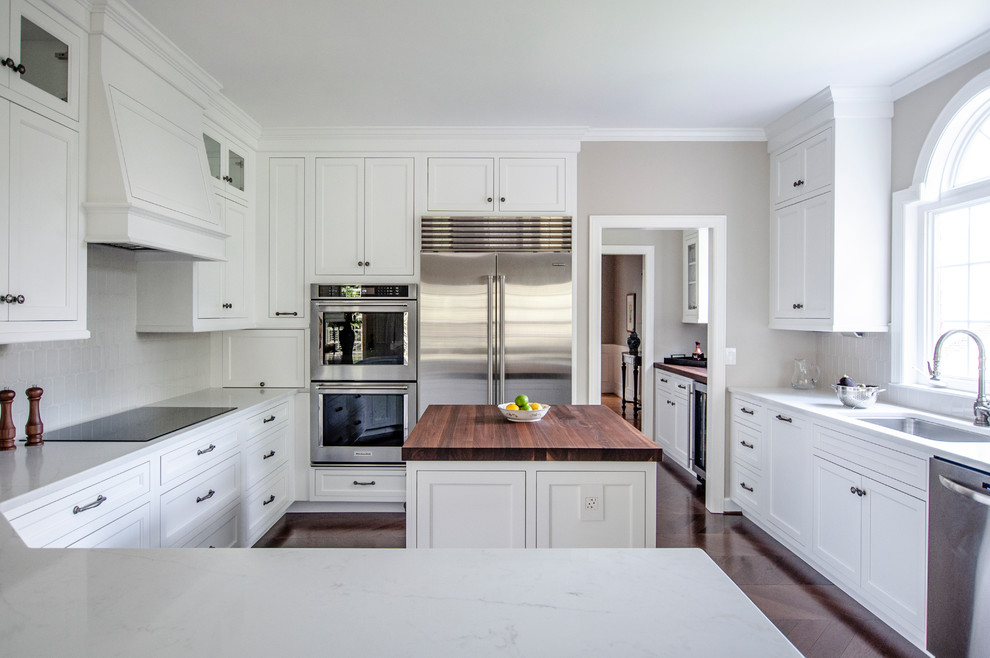Inspiration for a large transitional u-shaped kitchen in Nashville with an undermount sink, white cabinets, quartz benchtops, grey splashback, ceramic splashback, stainless steel appliances, dark hardwood floors, with island, brown floor, white benchtop and recessed-panel cabinets.