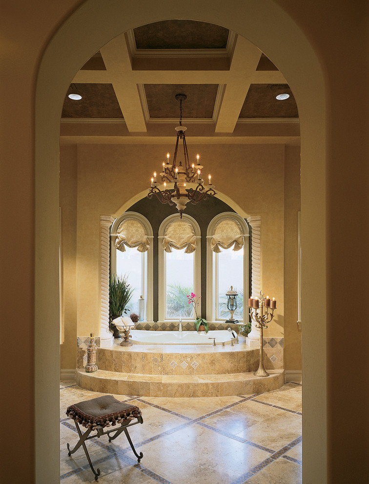 This is an example of an expansive mediterranean master bathroom in Miami with a drop-in tub, beige tile, stone tile, beige walls and travertine floors.