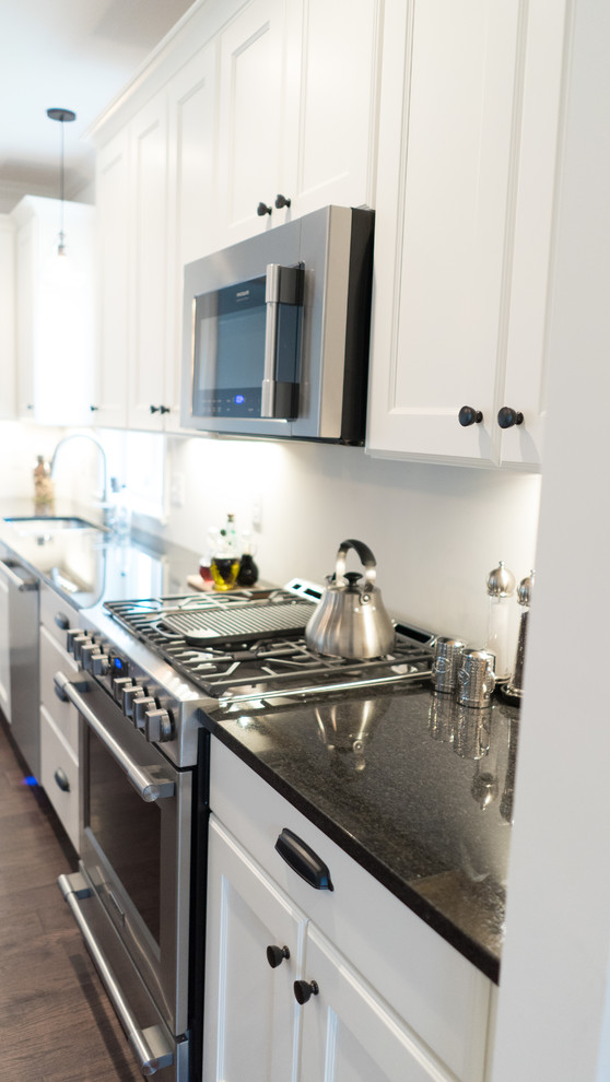 Mid-sized transitional l-shaped dark wood floor open concept kitchen photo with an undermount sink, shaker cabinets, white cabinets, granite countertops, gray backsplash, stainless steel appliances and an island