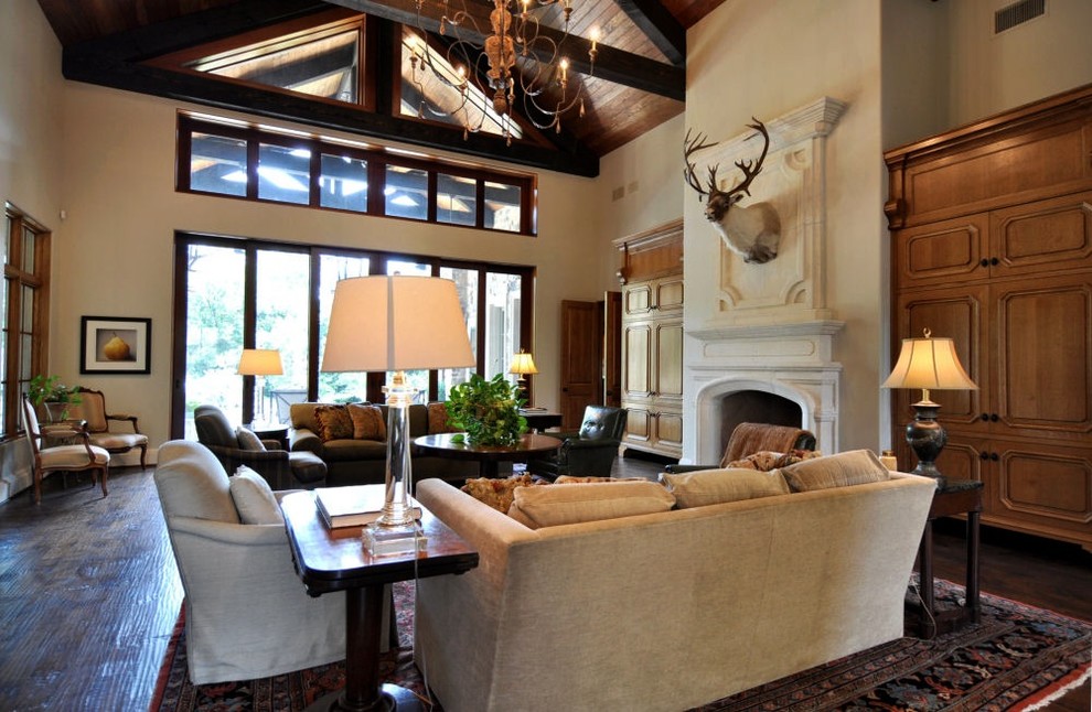 Inspiration for a large mediterranean open concept living room in Dallas with beige walls, dark hardwood floors, a standard fireplace, a stone fireplace surround and a concealed tv.