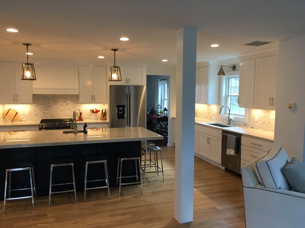 Mid-sized transitional u-shaped brown floor open concept kitchen photo in DC Metro with an undermount sink, shaker cabinets, white cabinets, gray backsplash, stainless steel appliances, an island and white countertops