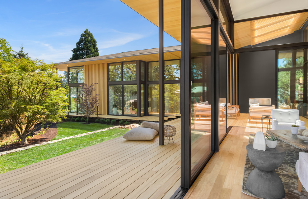 Photo of an expansive contemporary backyard deck in Portland with a fire feature and a roof extension.