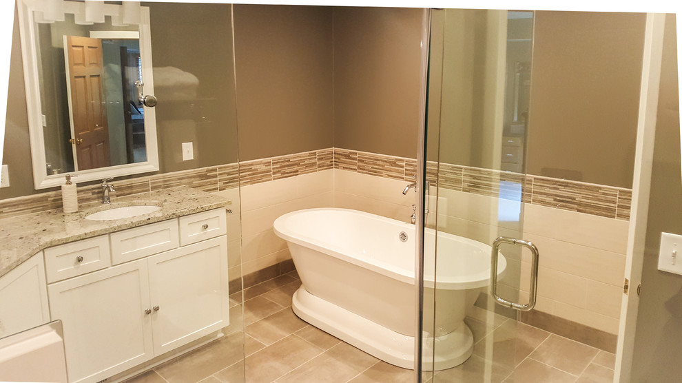 Large transitional master multicolored tile and ceramic tile porcelain tile and gray floor freestanding bathtub photo with shaker cabinets, white cabinets, a two-piece toilet, gray walls, an undermount sink, granite countertops and a hinged shower door