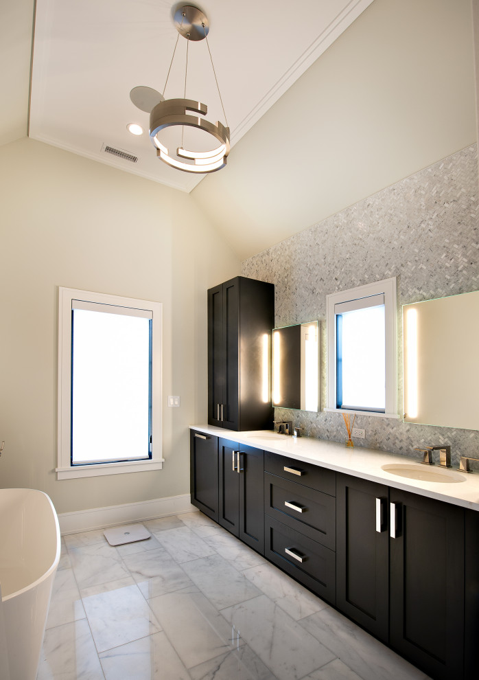 Пример оригинального дизайна: главная ванная комната среднего размера в современном стиле с фасадами в стиле шейкер, черными фасадами, отдельно стоящей ванной, угловым душем, унитазом-моноблоком, серой плиткой, керамогранитной плиткой, белыми стенами, полом из керамогранита, монолитной раковиной, столешницей из искусственного кварца, серым полом, душем с распашными дверями, белой столешницей, сиденьем для душа, тумбой под две раковины и встроенной тумбой