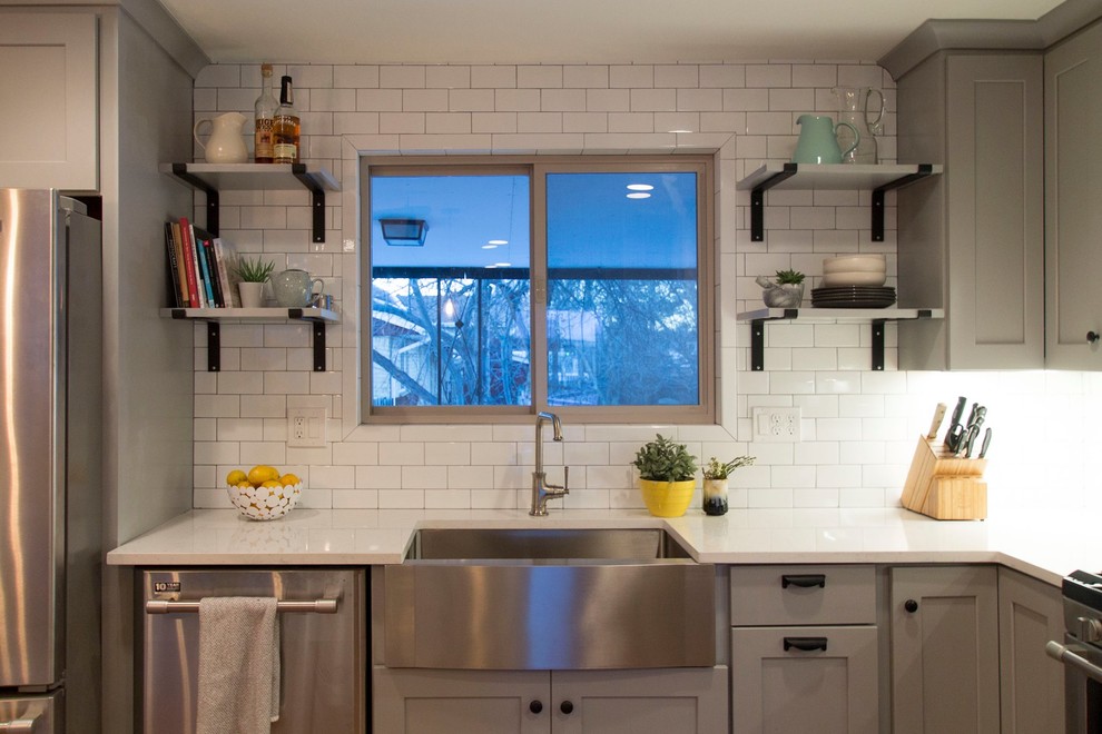 Eat-in kitchen - mid-sized transitional l-shaped medium tone wood floor eat-in kitchen idea in Denver with a farmhouse sink, shaker cabinets, gray cabinets, quartz countertops, white backsplash, ceramic backsplash, stainless steel appliances and an island