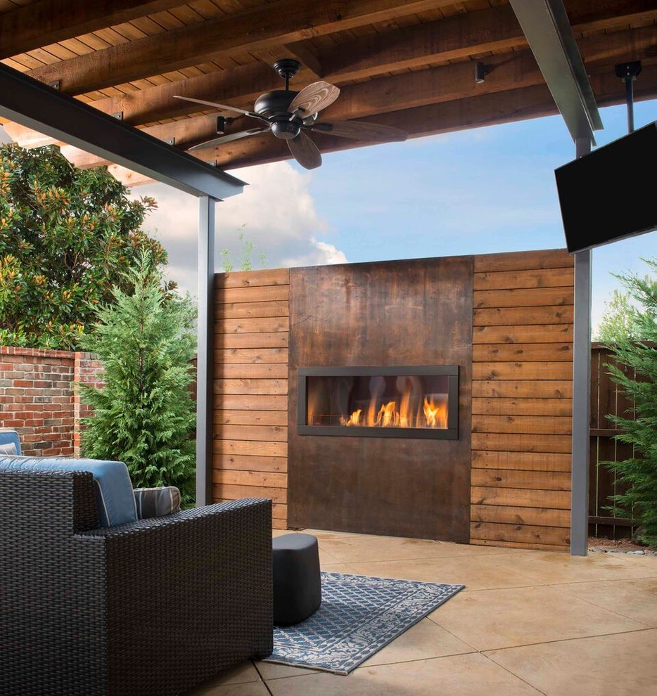 This is an example of a country backyard patio in Orange County with a fire feature, natural stone pavers and a roof extension.