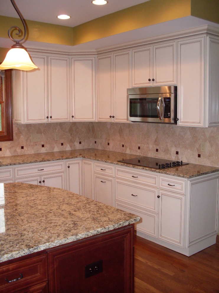 Example of a mid-sized transitional u-shaped dark wood floor open concept kitchen design in Cincinnati with an undermount sink, recessed-panel cabinets, white cabinets, granite countertops, beige backsplash, ceramic backsplash, stainless steel appliances and an island