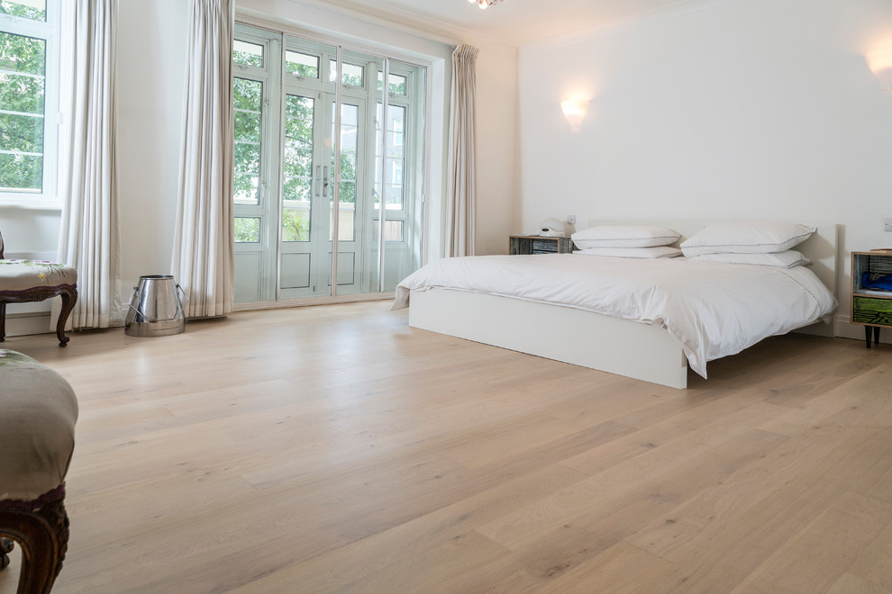 Example of a large trendy master light wood floor and beige floor bedroom design in Denver with white walls and no fireplace