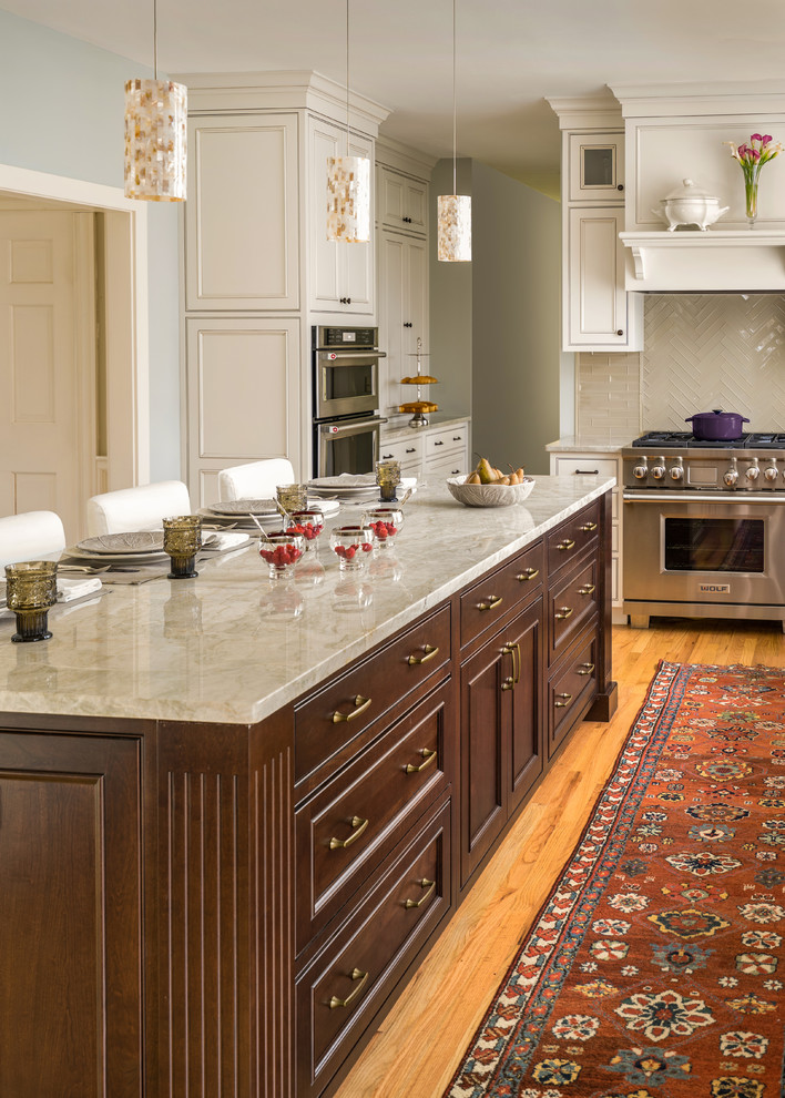 Inspiration for a large traditional l-shaped eat-in kitchen in Boston with an undermount sink, recessed-panel cabinets, white cabinets, granite benchtops, grey splashback, glass tile splashback, stainless steel appliances, light hardwood floors, with island and brown floor.